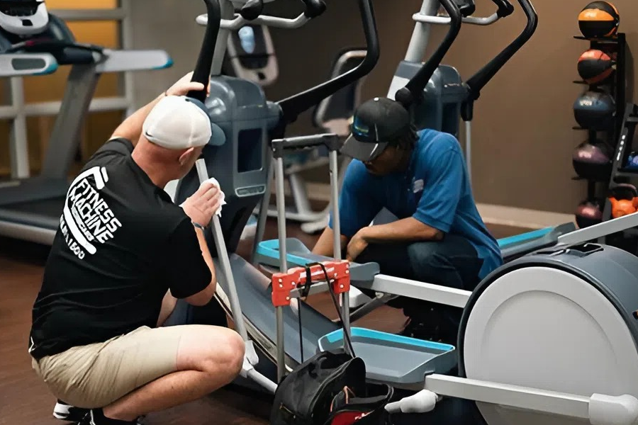 Fitness equipment technicians inspecting cardio machines for repair or replacement decisions
