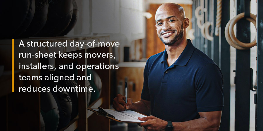 Gym relocation lead reviewing a written move-day run-sheet to coordinate movers, installers, and operations teams